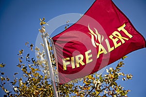 Red Flag in wind with yellow letters reading `Fire Alert` photo